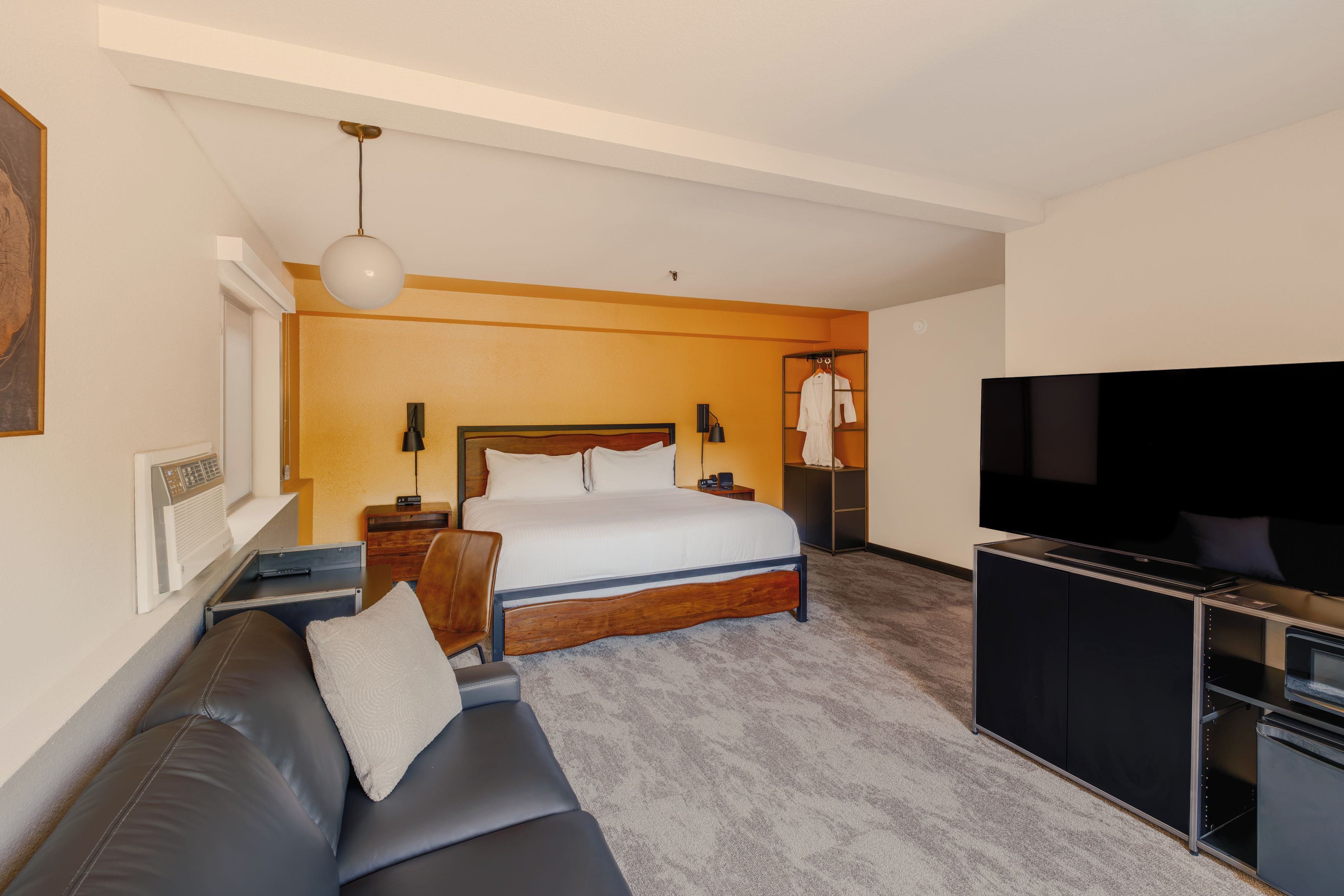 Ein Hotelzimmer mit Bett, Fernseher, Sofa und Kleiderschrank.