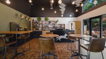 A cafe interior with wooden tables and chairs, a counter with plants, and a wall with a wolf mural.
