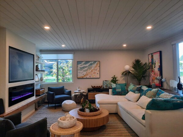 A modern living room with a flat-screen TV, comfortable seating, a coffee table, and artwork on the walls. - Southern Cal vacation in 55+ lovely Laguna Woods. Month long rental. (Laguna Woods)