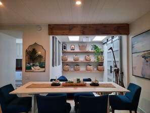 A dining area with a wooden table, blue chairs, and shelves with baskets. - Southern Cal vacation in 55+ lovely Laguna Woods. Month long rental. (Laguna Woods)