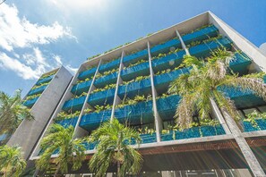 A modern building with multiple balconies, each with blue-tiled railings and greenery. - Vibrante y Moderno Estudio Cerca de Quinta Avenida (Playa del Carmen)