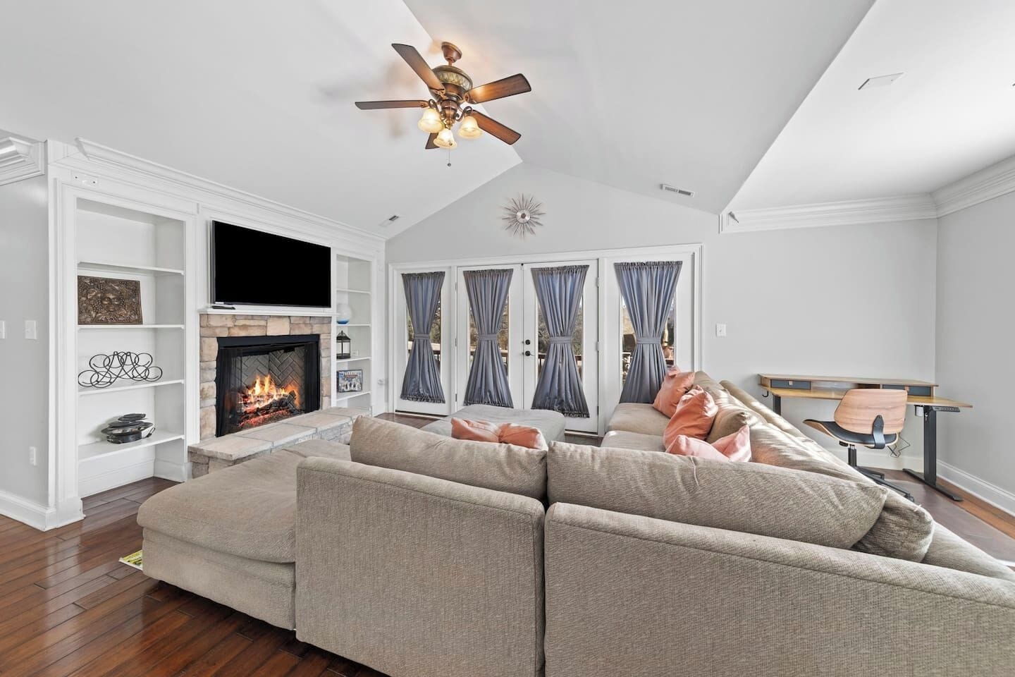 A living room with a fireplace, a ceiling fan, and a large sectional sofa.