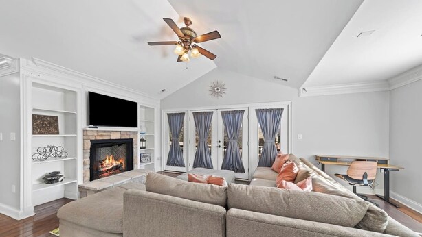 Una sala de estar con chimenea, ventilador de techo y un amplio sofá seccional.