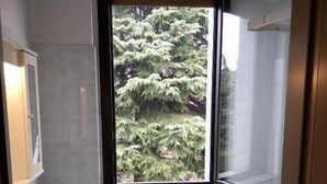 Ein modernes Badezimmer mit großem Fenster, zwei Toiletten, einem Waschbecken und einer Heizung.