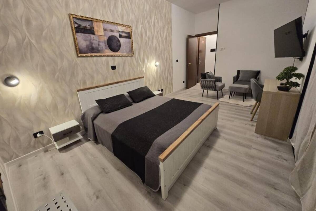 A modern bedroom with a bed, bedside table, and a TV mounted on the wall.