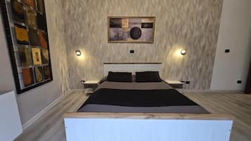 Un dormitorio moderno con una cama grande, una pared con textura y una obra de arte enmarcada sobre la cama.