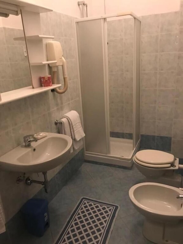 A bathroom with a sink, toilet, bidet, and a walk-in shower. - Hotel Cristallo (Novara)