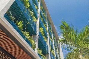 Een modern gebouw met verticale tuinen en een helderblauwe lucht.