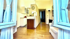 A hotel room with a wooden floor, a desk with a lamp, a clock on the wall, and a view through a doorway. - Sant'Onofrio - Trastevere Vatican apartment in Rome (Roma)