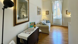 A cozy room with a wooden floor, a desk with a map, a sofa, and a window with curtains. - Sant'Onofrio - Trastevere Vatican apartment in Rome (Roma)
