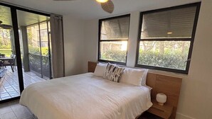 Una camera da letto con un letto, una ventola a soffitto e ampie finestre.