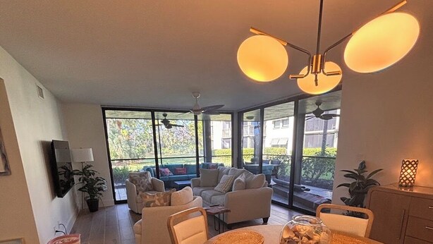 Un'area pranzo moderna con un tavolo rotondo in legno, sottopiatti intrecciati e una ventola a soffitto.