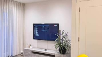 Una sala de estar moderna con un televisor de pantalla plana, una mesa de centro y dos sillas amarillo brillante.