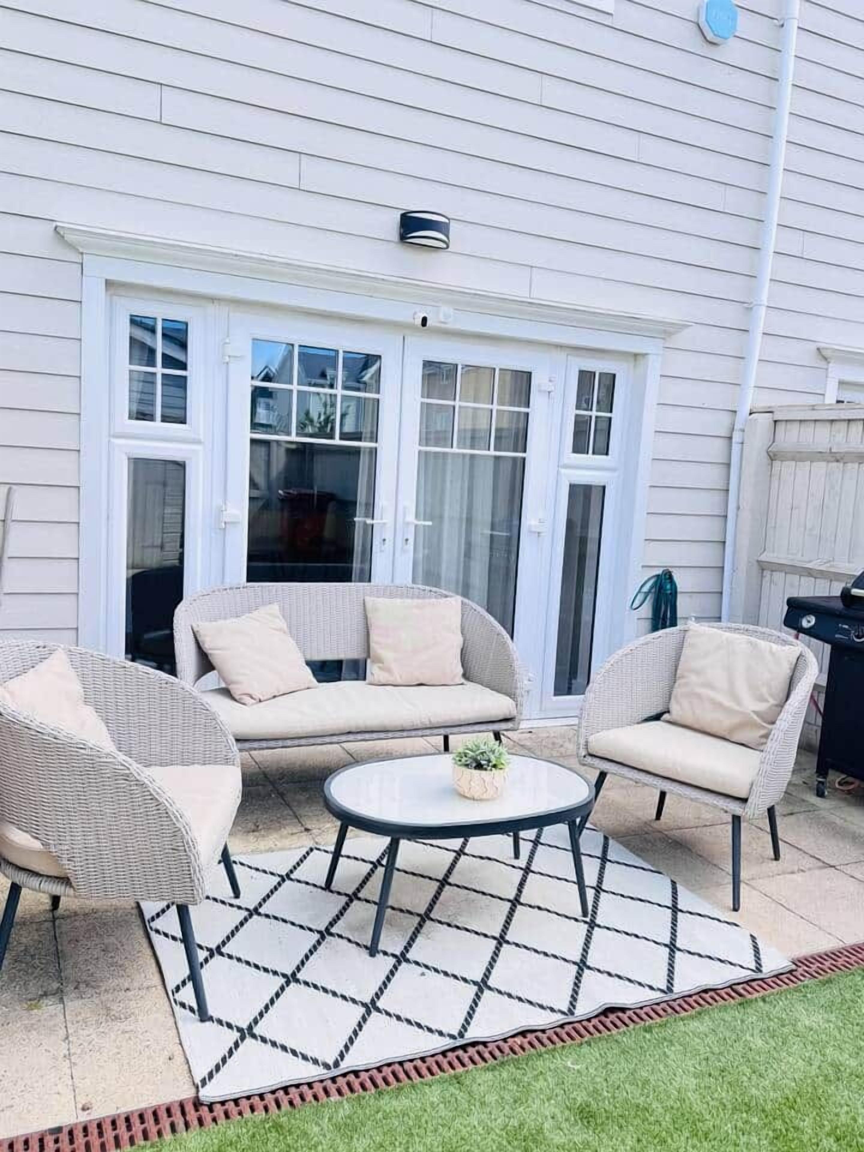 A patio with wicker furniture, a round table, and a small potted plant.