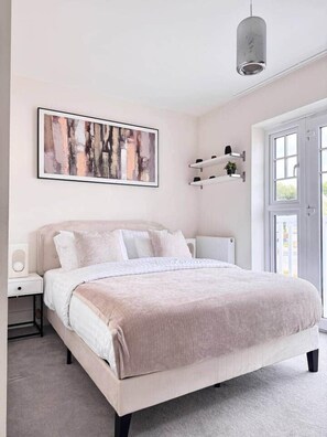 Une chambre à coucher comprenant un lit, une table de chevet, un radiateur, une fenêtre et une étagère fixée au mur, sur laquelle se trouve une plante.