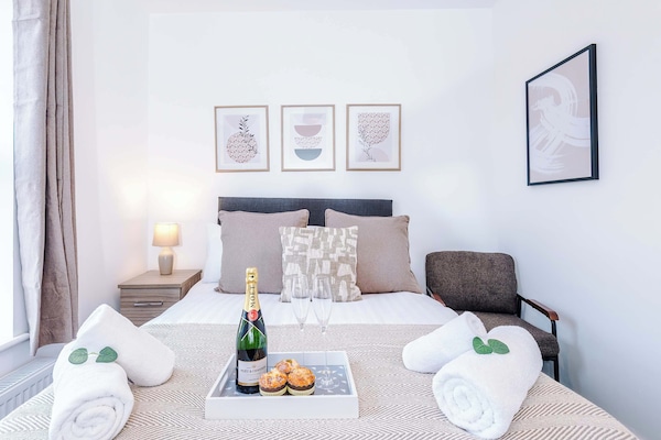 Double bedroom furnished with a double bed and upholstered headboard, bedside tables with lamps, and wall-mounted artwork. Finished with soft carpeting, neutral décor, and neatly dressed bedding.