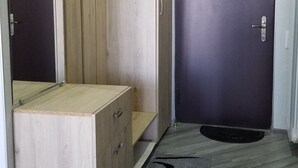Ein Zimmer mit einem Holzschrank, einem Bett, einer dunklen Tür und einem gemusterten Teppich.