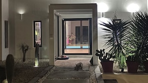 A modern house entrance with a pathway leading to a door, surrounded by potted plants and a small dog bed. - Villa SANDI luxury and comfort - a contemporary oasis. Ideal for vacations (Saint-François)