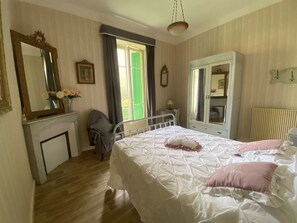 Ein Schlafzimmer mit einem Bett, einem Schminktisch, einem Sessel und einem Spiegel.