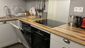 A modern kitchen with a wooden countertop, stainless steel appliances, and a dishwasher. - Apartment Iris II - Menton City Centre (Menton)