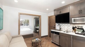 A modern kitchen with stainless steel appliances, a dining area with a white table and chairs, and a large window providing natural light. - Park City, Ski-in, Ski-out, 2-bed 2 bath, Sleeps 8 (Park City)