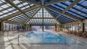 An indoor swimming pool with a glass ceiling, lounge chairs, and a visible steam feature. - Park City, Ski-in, Ski-out, 2-bed 2 bath, Sleeps 8 (Park City)