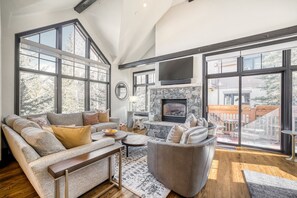 Ein geräumiges Wohnzimmer mit Kamin, großen Fenstern und Blick ins Freie.