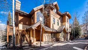 Una grande casa a più piani con un portico sporgente, una scalinata e un vialetto che conduce a un garage.