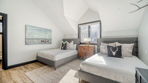 Una camera da letto con due letti, un armadietto in legno, un quadro e una ventola a soffitto.