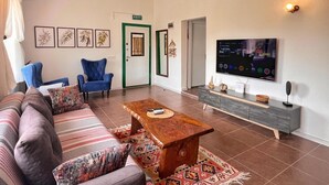 Una sala de estar con un sofá, sillas, una mesa de centro, un televisor y una puerta con marco verde.