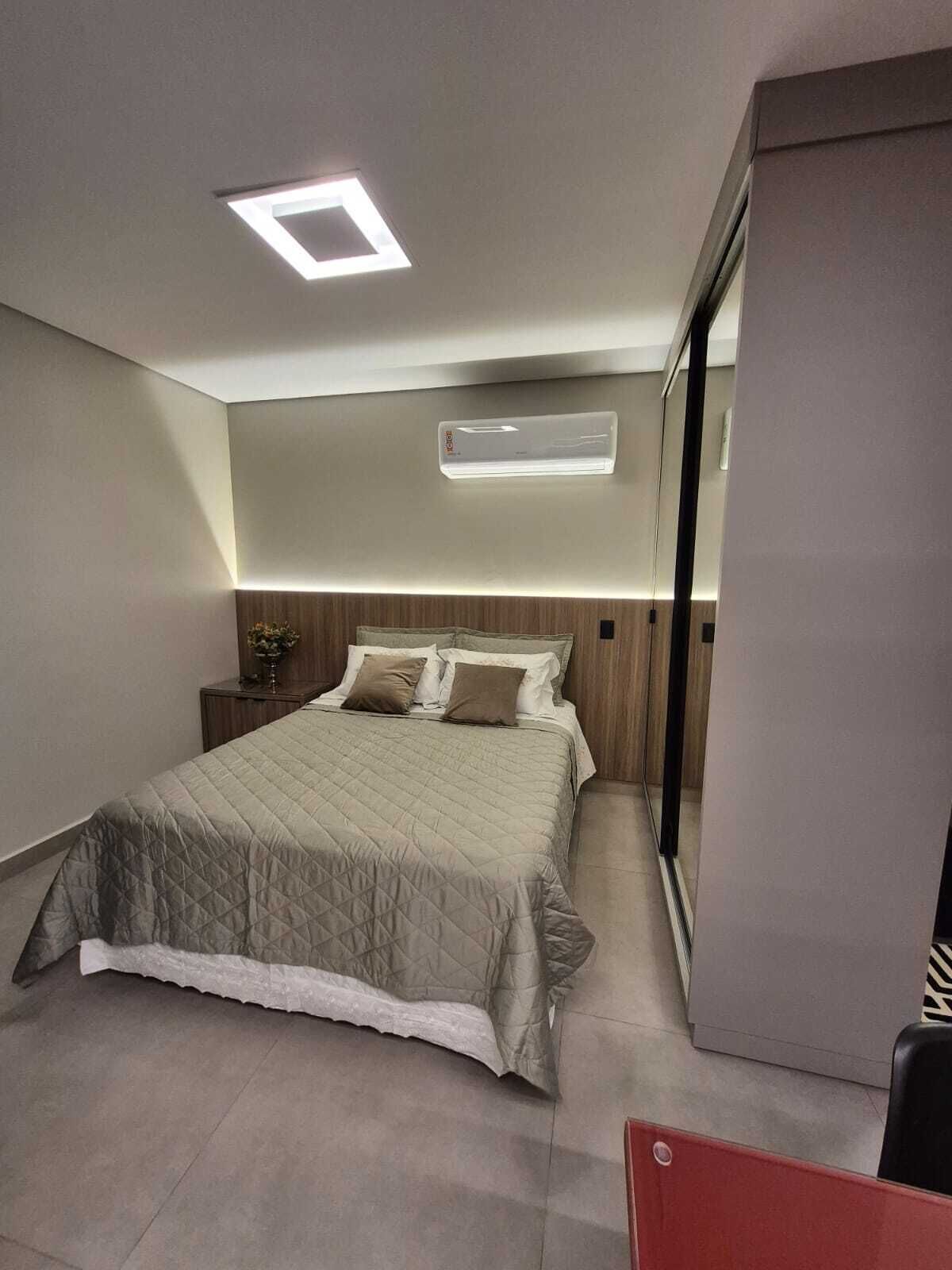 A modern bedroom with a bed, bedside tables, a nightstand, a mirror, and a wardrobe.