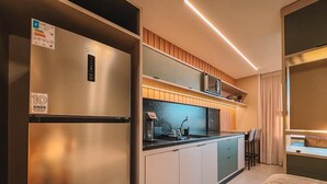 Une cuisine compacte équipée d’un réfrigérateur intégré, d’un four à micro-ondes et d’un évier.