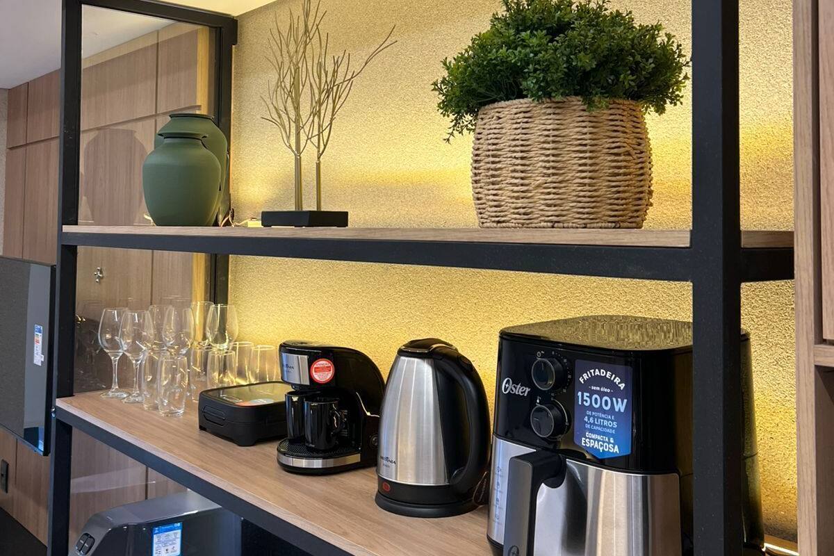 A modern kitchen with a coffee maker, kettle, and glassware on the counter.