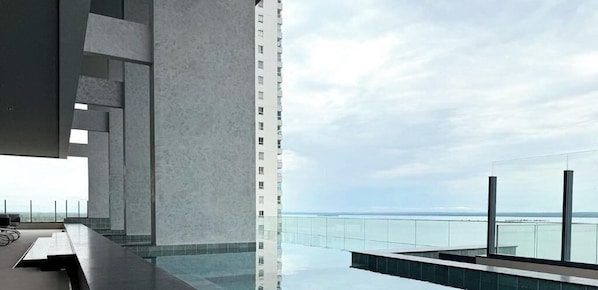 A modern building with a pool and a view of the sea.