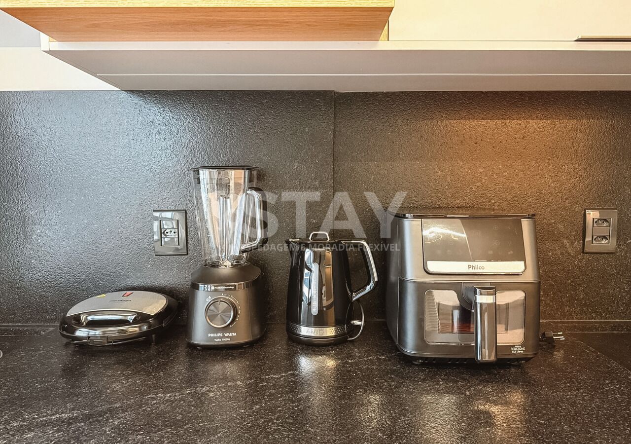 A kitchen with a blender, coffee maker, and kettle on a countertop.
