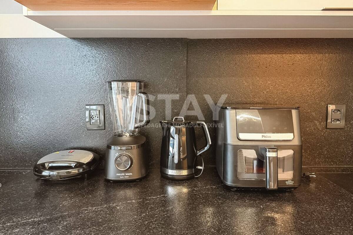 A kitchen with a blender, coffee maker, and kettle on a countertop.