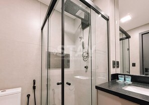 A modern bathroom with a glass shower enclosure, a sink, and a mirror.