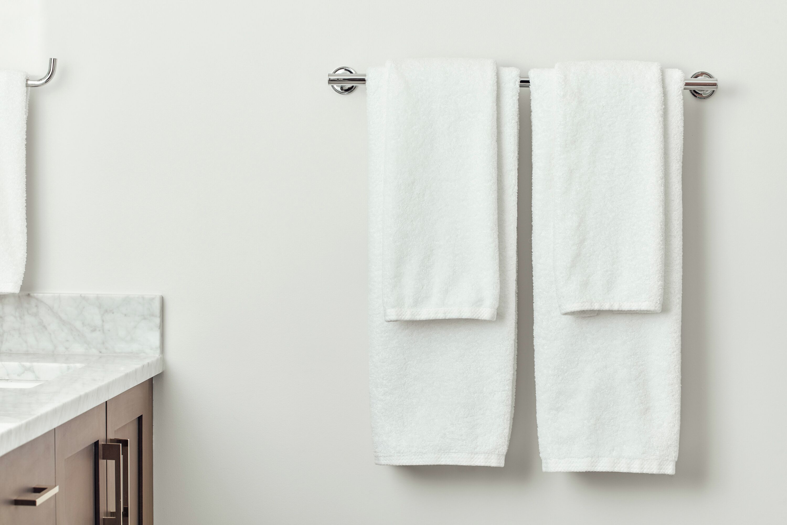 A bathroom with two white towels hanging on a metal towel bar.