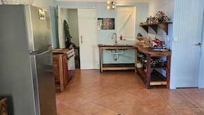 Cocina compacta con refrigerador, lavamanos y estantes de madera.