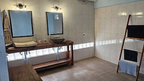 Un baño con tocador de madera, un espejo grande y un perchero para toallas.