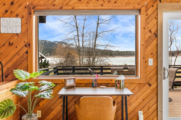 A wooden cabin with a large window overlooking a river and trees.