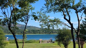 A grassy area with trees and a lake. - Conrad Vista | Fully Remodeled Waterfront Retreat (Priest River)