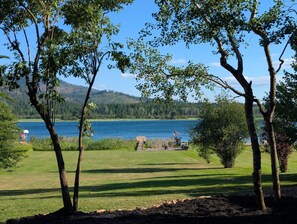 A grassy area with trees and a lake.