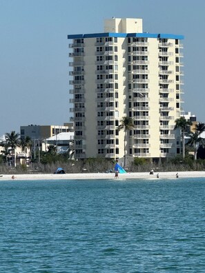 A high-rise hotel with multiple balconies, located near a beach with palm trees and a sandy shore. - Charming, updated 1-bedroom Beach Condo w/ great pool & lots of beach unit 301. (Fort Myers Beach)