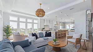 A spacious living area with a sofa, coffee table, and a view of the kitchen and dining area. - Seaclusion l Luxury l Heated Pool l Beach (St. Augustine)