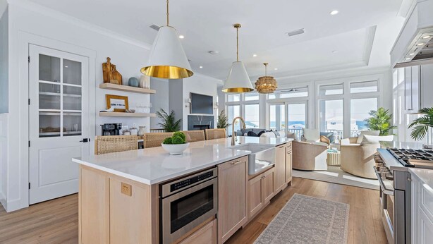 A modern kitchen with a central island, white cabinetry, and pendant lighting. - Seaclusion l Luxury l Heated Pool l Beach (St. Augustine)