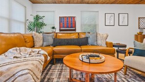 Ein gemütliches Wohnzimmer mit einem braunen Ledersofa, einem Holztisch und einem gemusterten Teppich.