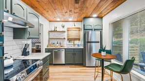 Eine moderne Küche mit Holzbalkendecke, Edelstahlgeräten und einem Essbereich mit Tisch und Stühlen.