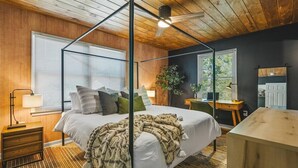 Ein Schlafzimmer mit einem Himmelbett, einem Schreibtisch und einem Sessel.