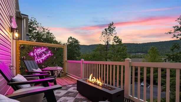 Eine Terrasse mit Sitzgelegenheiten im Freien, einem Feuerkorb und einem Neonzeichen.